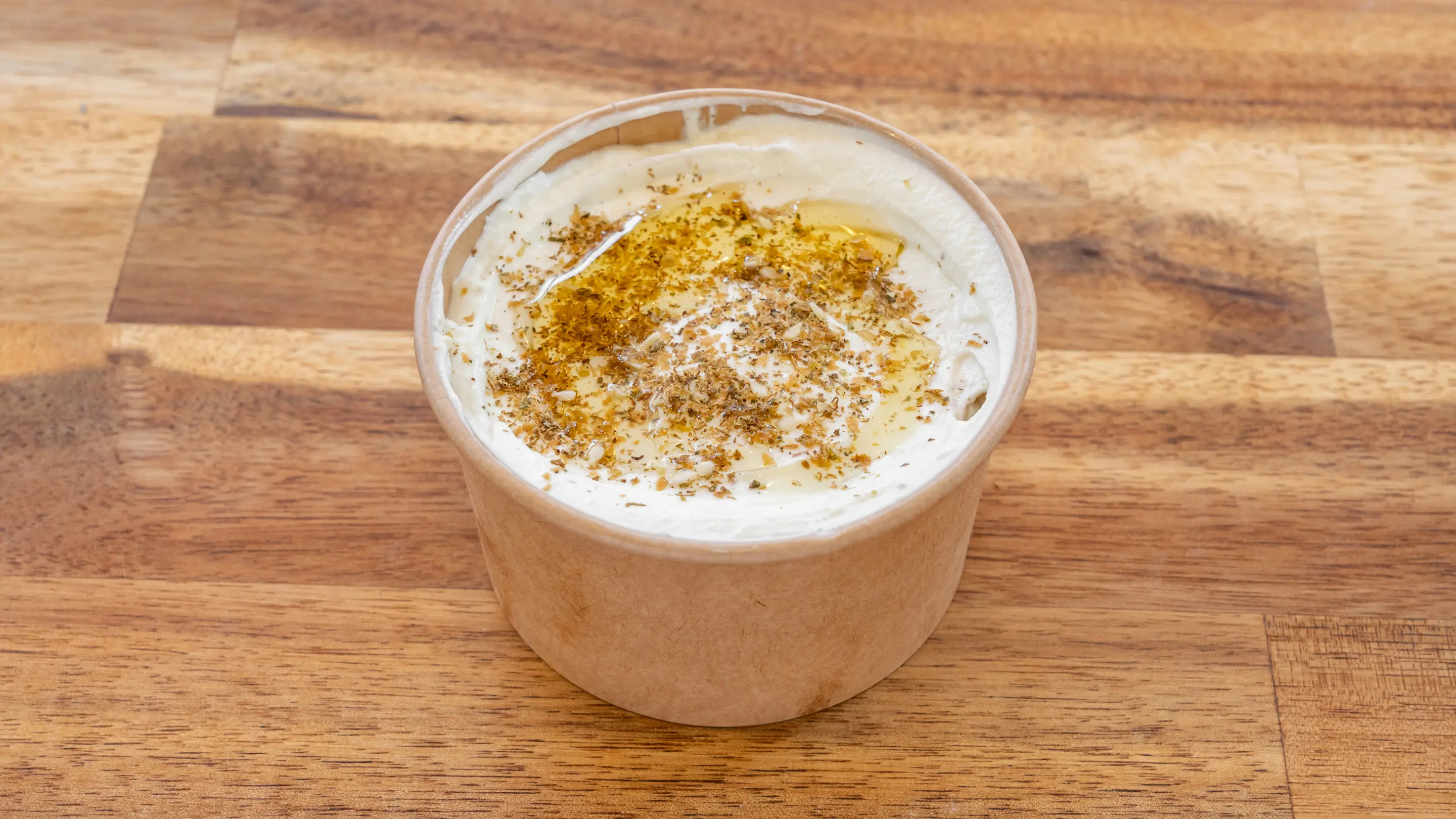 Labné dans un pot kraft avec un filet d’huile d’olive et du zaatar