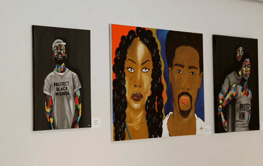 Three portraits displayed at the Grace Trinity art show, featuring colorful and powerful depictions of people.