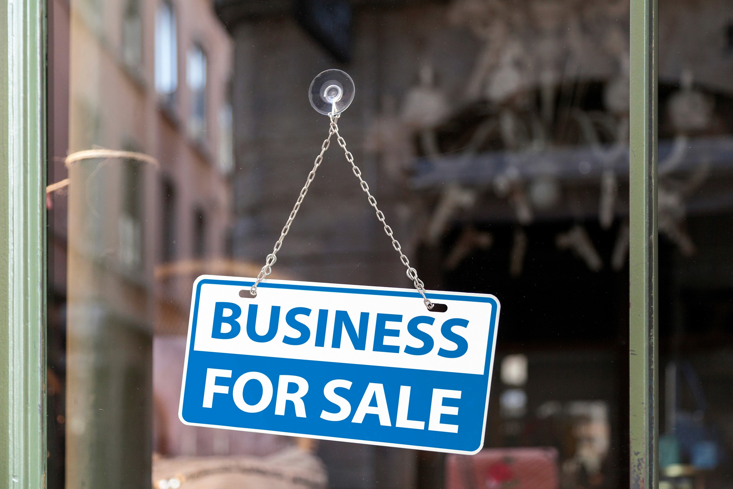 Close-up on a white and blue sign in a window written inside it "Business for sale".
