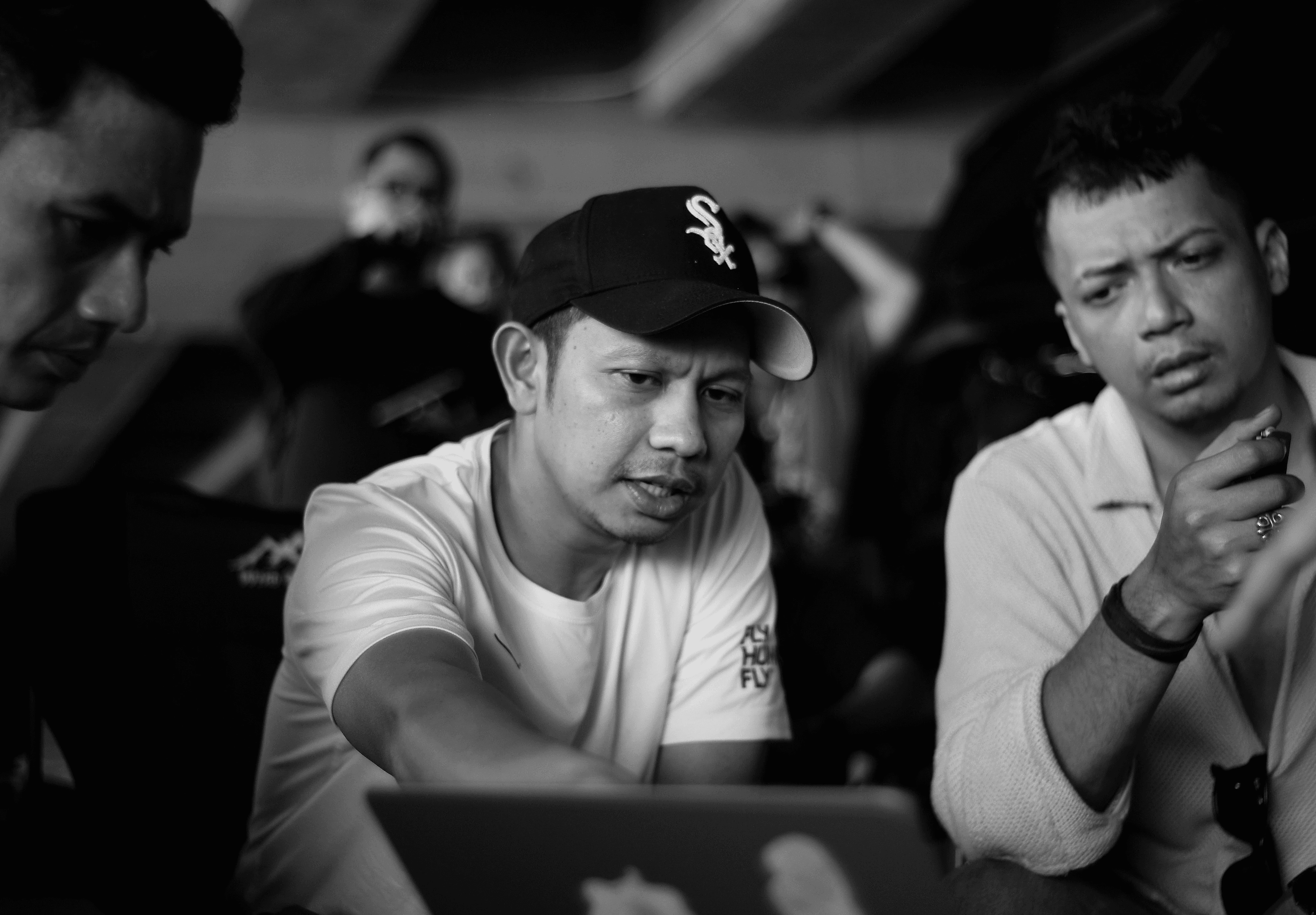 Three men gathered around a laptop computer.