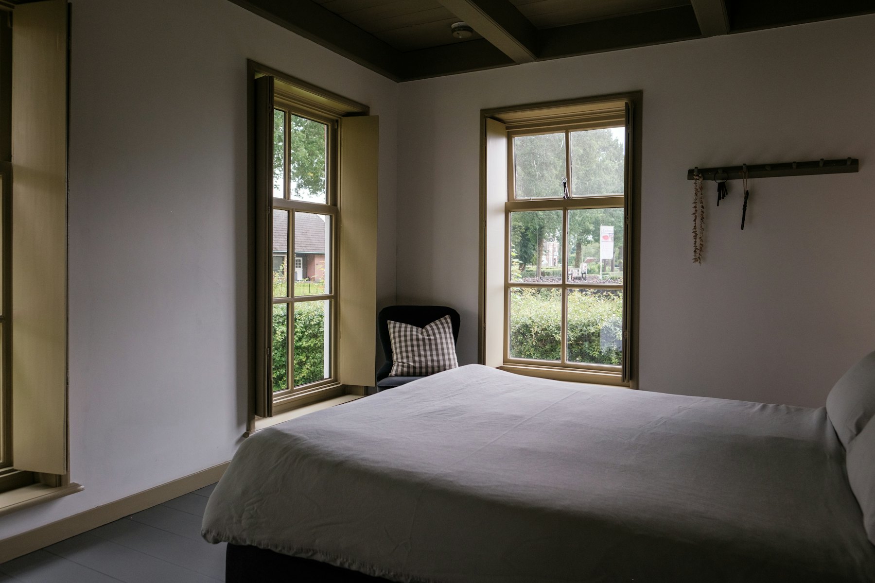 Bright bedroom with two windows and a made bed