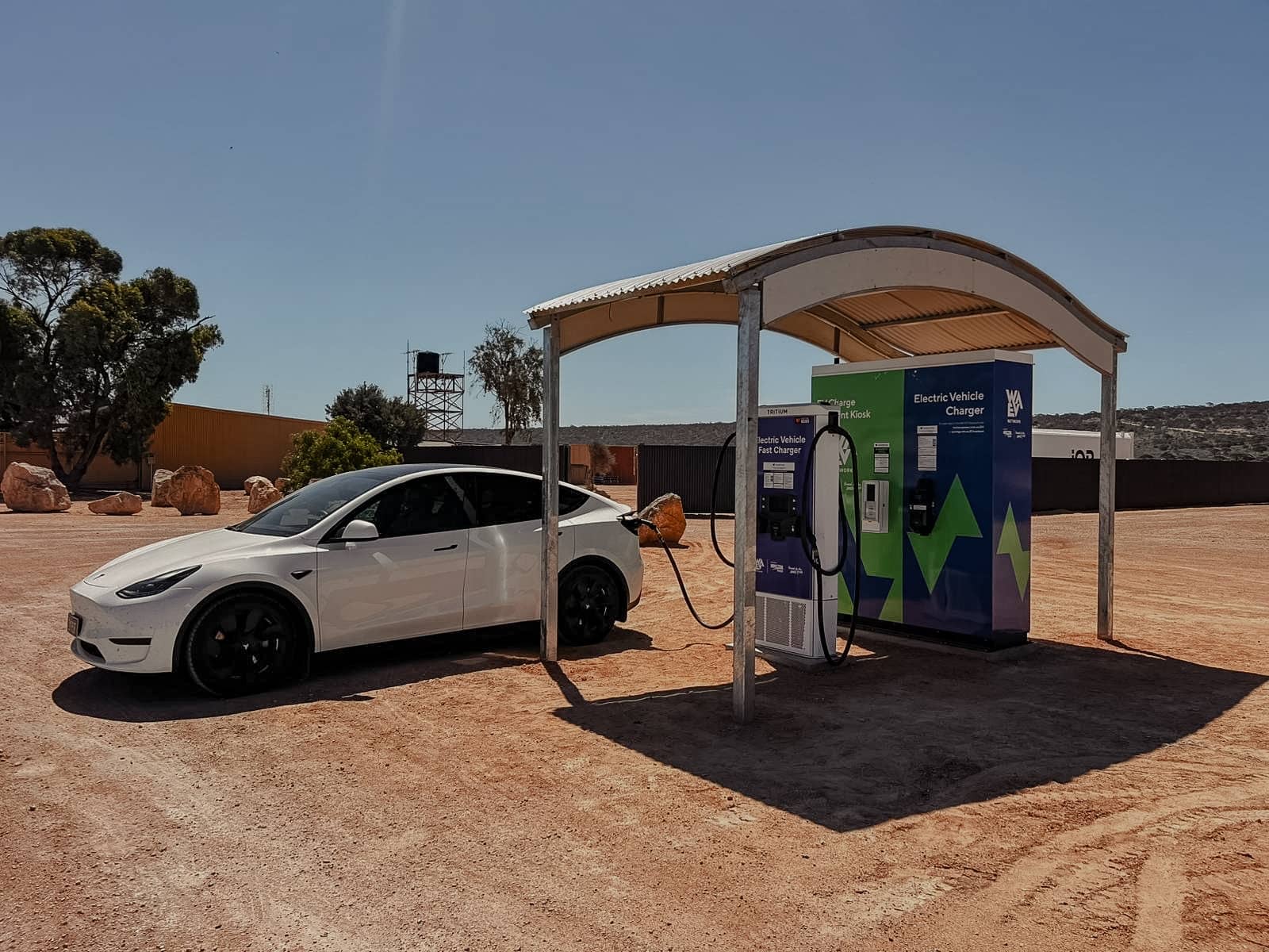 White Tesla charging at an electric vehicle fast charger in remote Western Australia.