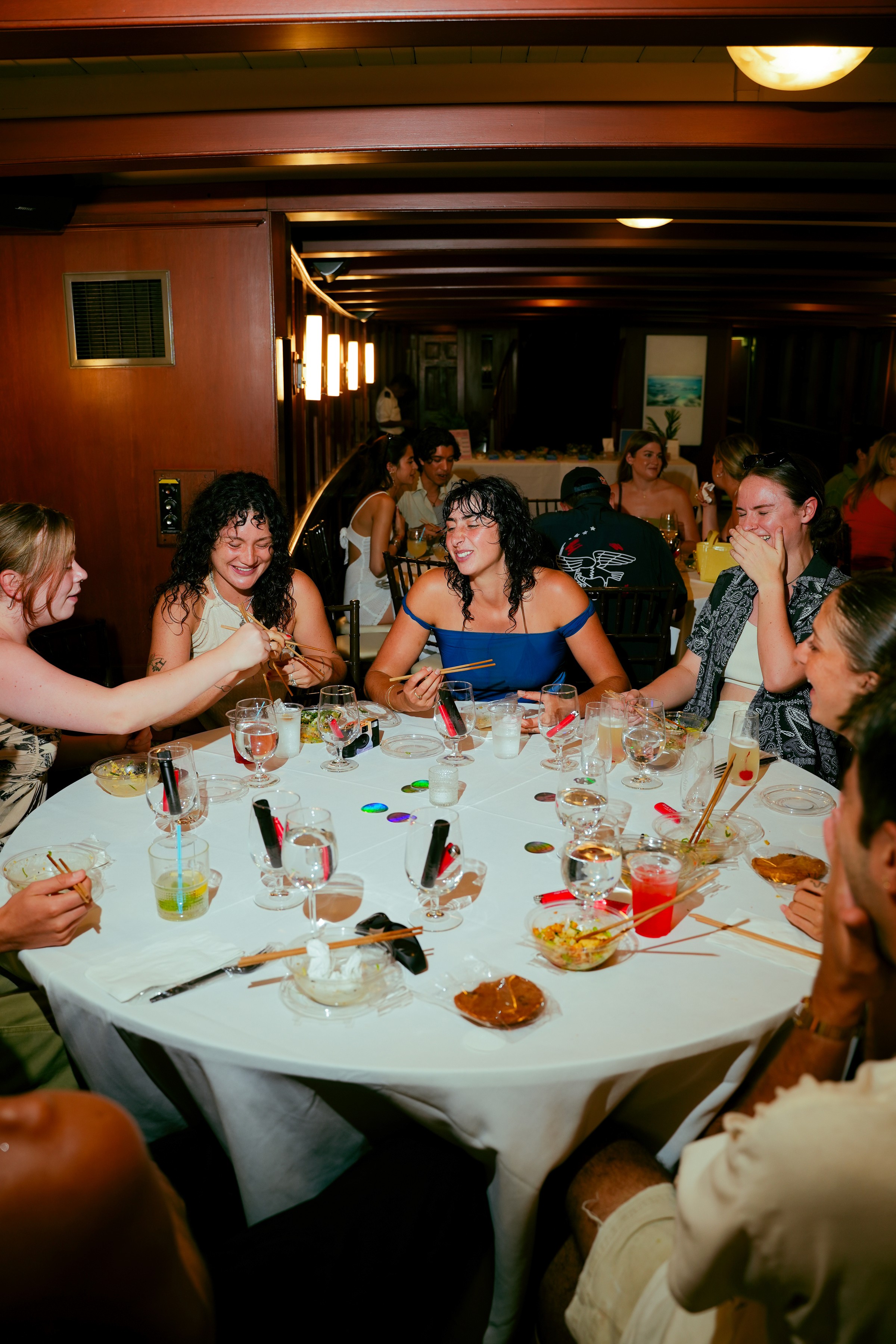A group of people seated at a table, enjoying a meal and drinks in a lively restaurant setting.
