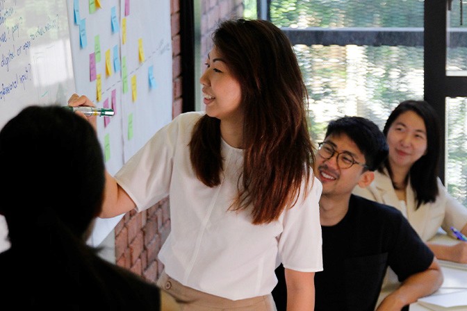 An image of Wendy, our Co-Founder and Head of 55 Minutes, leading a discussion at a whiteboard while other members listen and take notes.