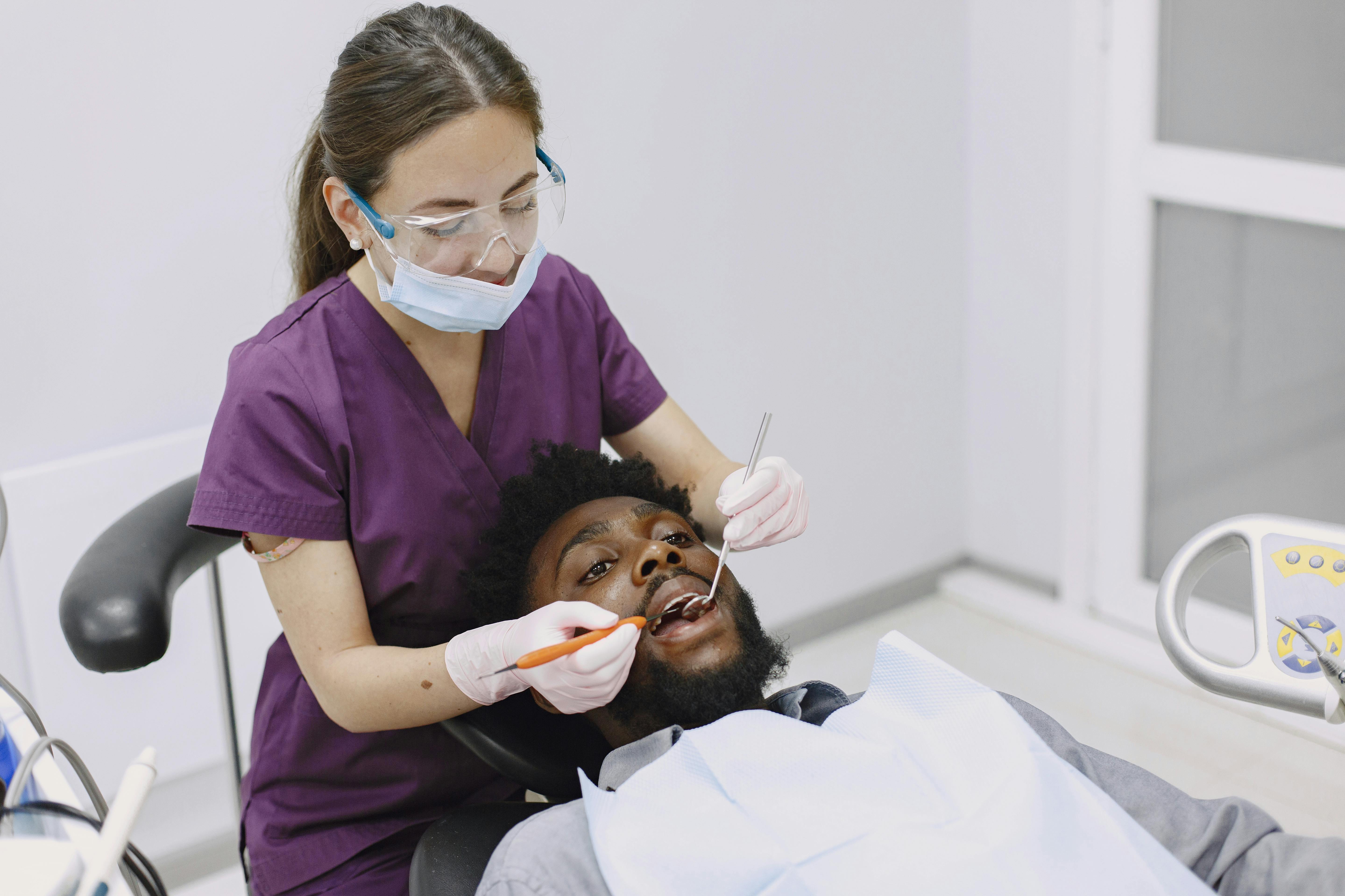 dental hygienist sitting in ergonomic chair helping patient