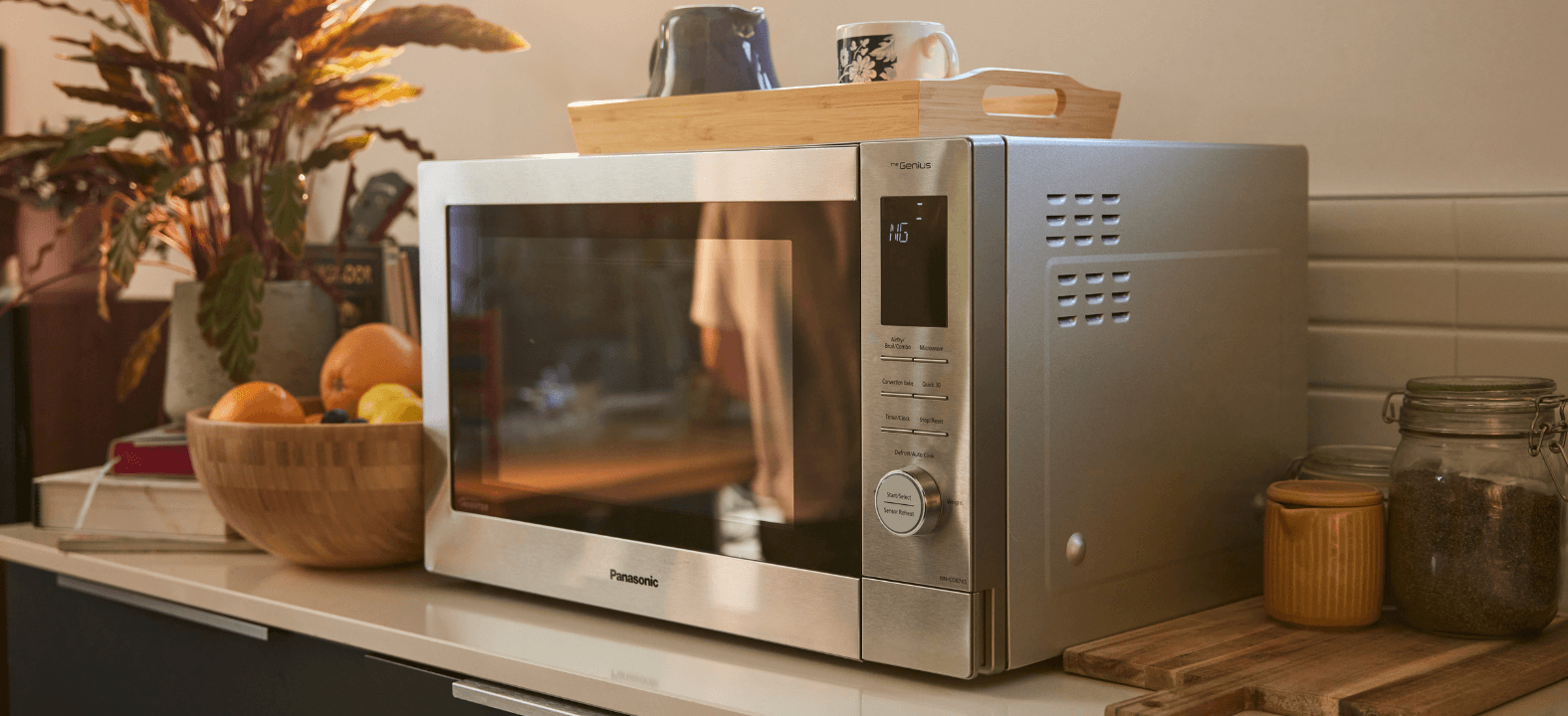 Panasonic 4 in 1 multi oven sits on a kitchen counter with a bowl of fruit and a wooden tray on top