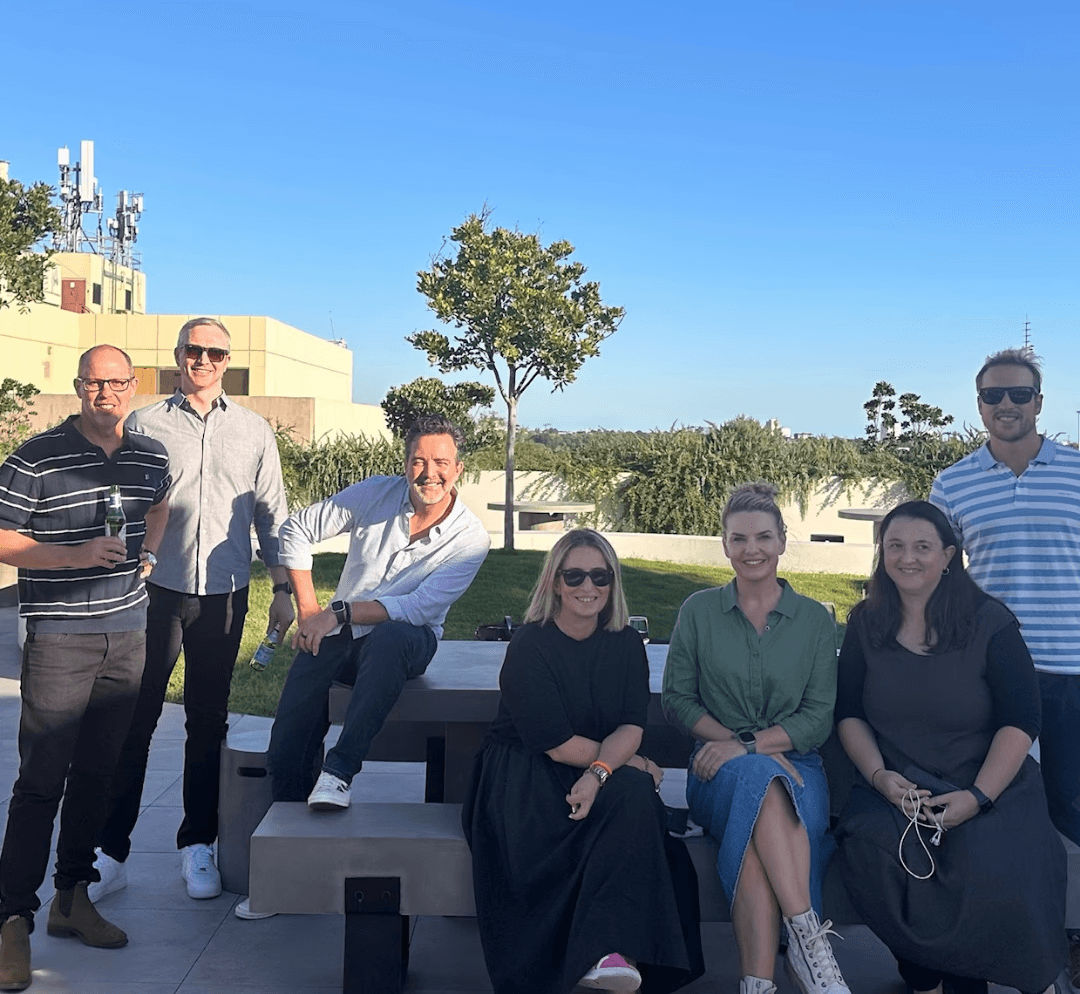 Smiling group of individuals standing together on a rooftop, sharing a joyful moment.