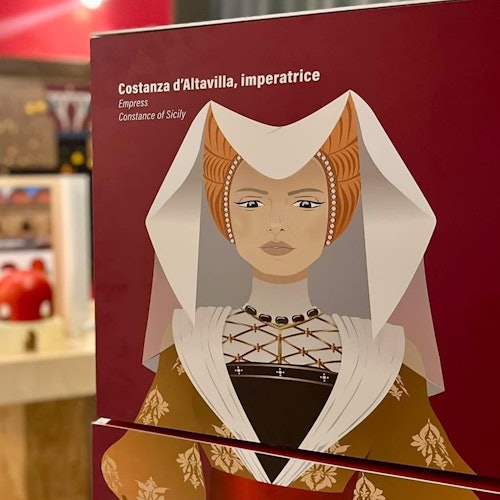 シチリアのコンスタンスが歴史的な衣装で赤い背景に描かれており、彼女を皇后として識別するテキストが上にあります。