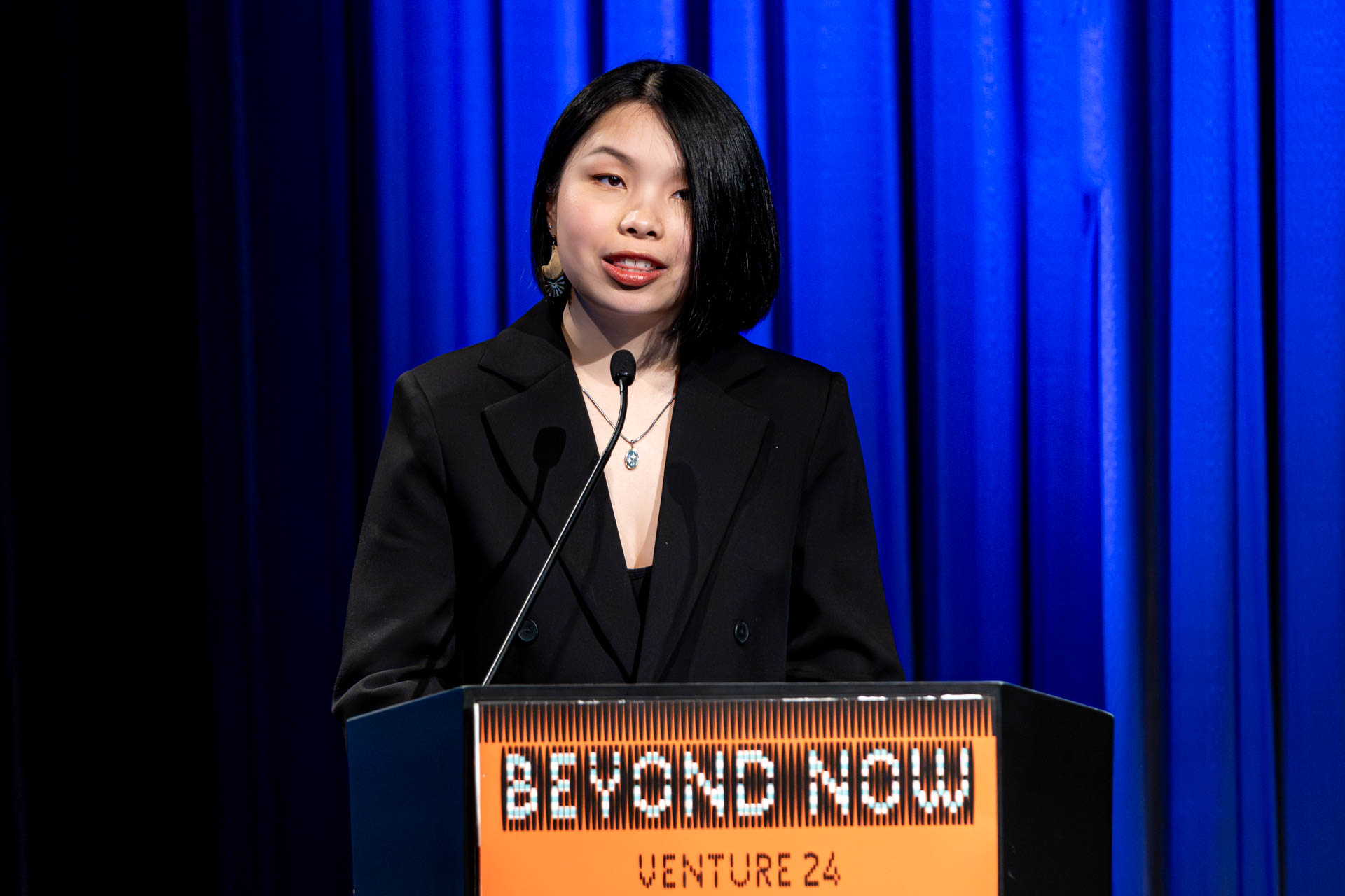 a student at a podium presenting a project in a Theatre