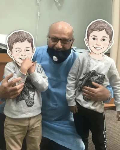 Dr. Ashraf Saddik kneeling with two young child patients at his Melbourne medical clinic.