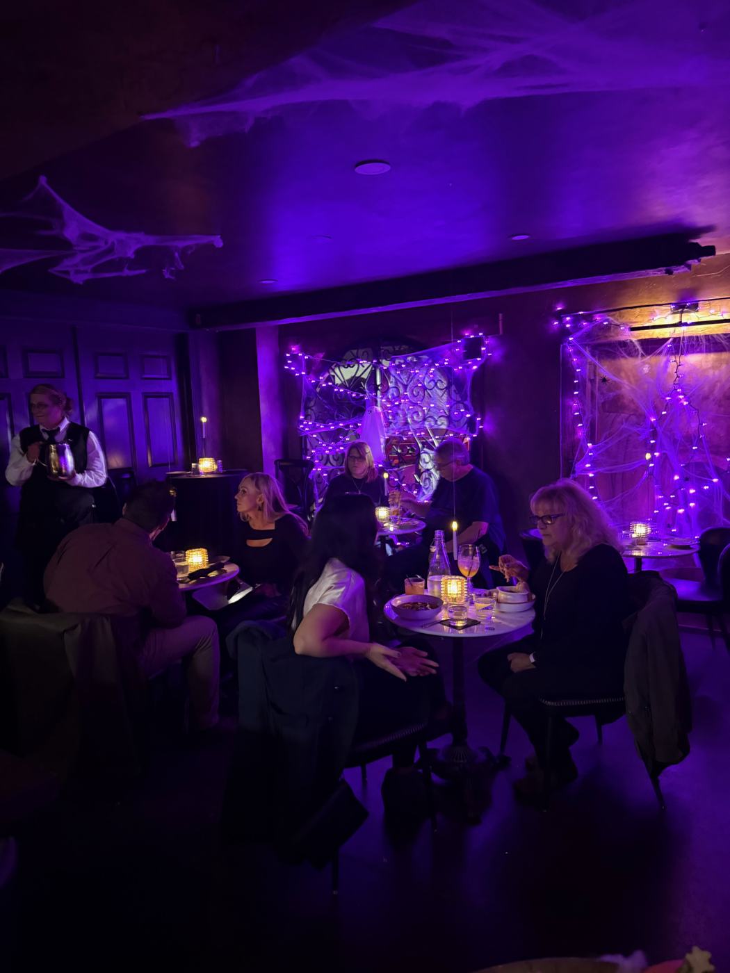 The dining room lit purple for Halloween, with guests at candlelit tables