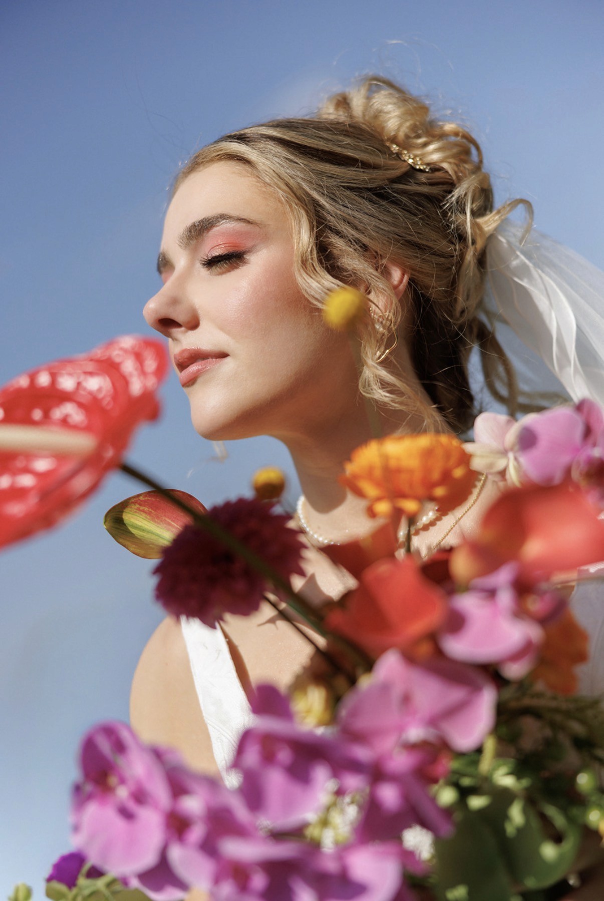 Luxury fashion editorial photography featuring model in vibrant patterned suit with orange accents, seated on vintage green armchair in elegant interior setting - Serif Creative Studio portfolio