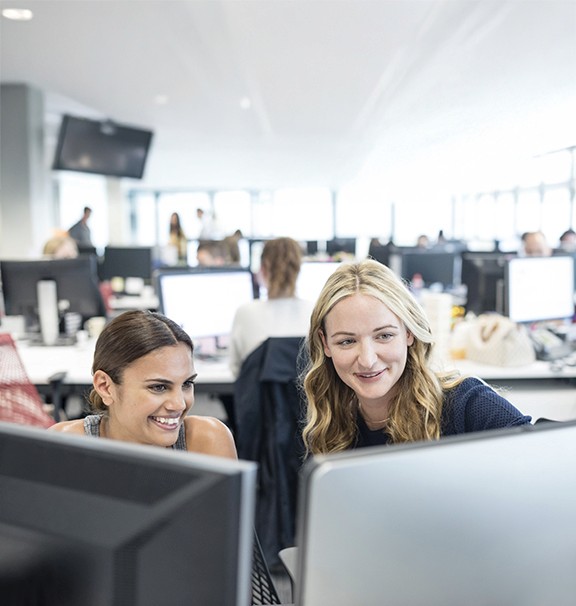 two female medical coders, one brunette and one blonde, working at computer monitors