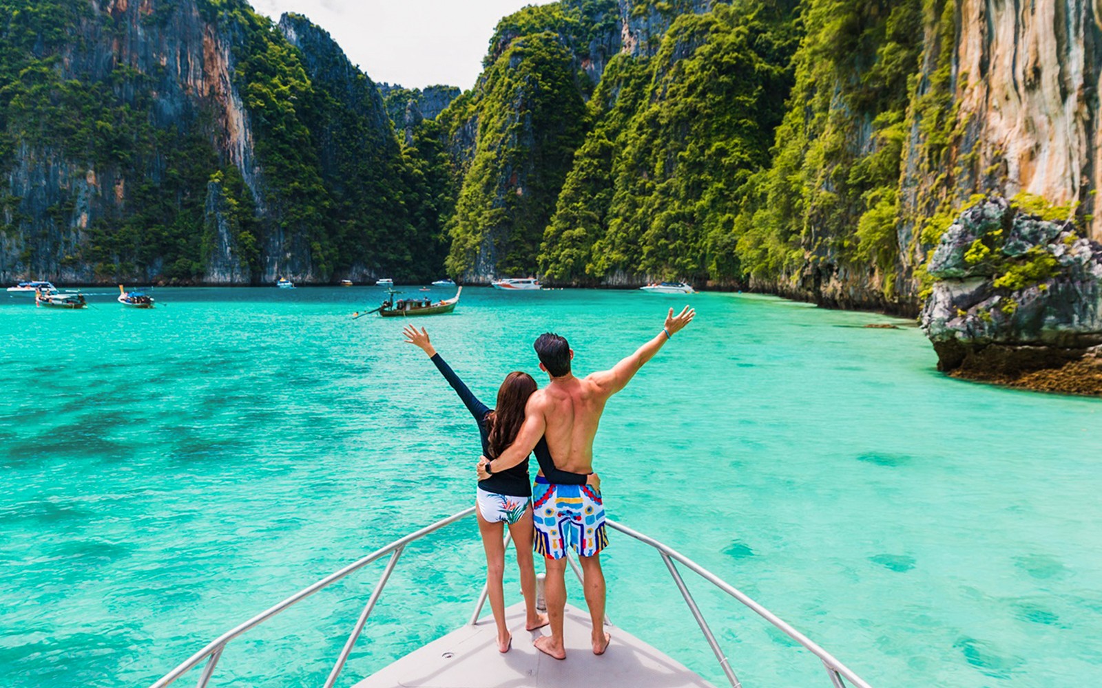 一对夫妇乘船探索皮勒泻湖，四周环绕着悬崖和碧绿的海水。