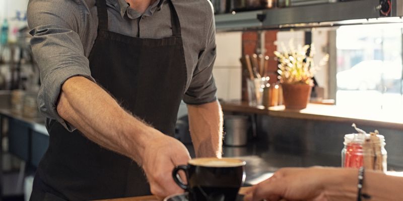 An F&B staff serving coffee to a customer