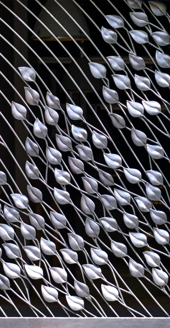 A large-scale architectural metal gate featuring a fluid pattern of silver, metallic hand-forged leaves climbing up diagonal bars. An architectural objet d’art installation designed by Shaun Leane for his new independent design studio.