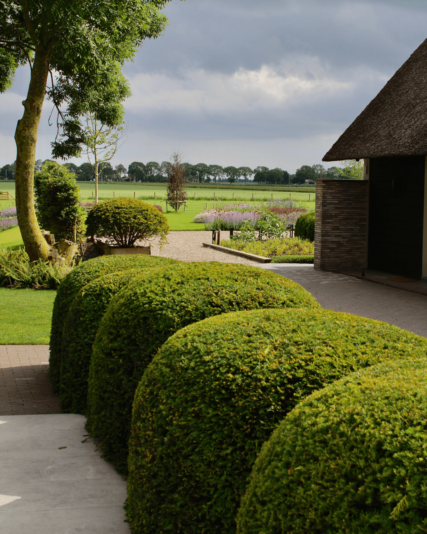 Modern bathroom featuring a walk-in shower, wooden vanity, round mirror, and elegant marble tiles.