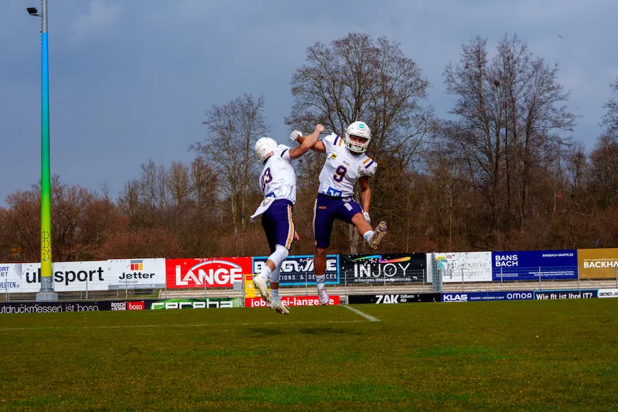 Zwei Spieler der Bucks springen auf dem Spielfeld in die Luft und feiern gemeinsam.