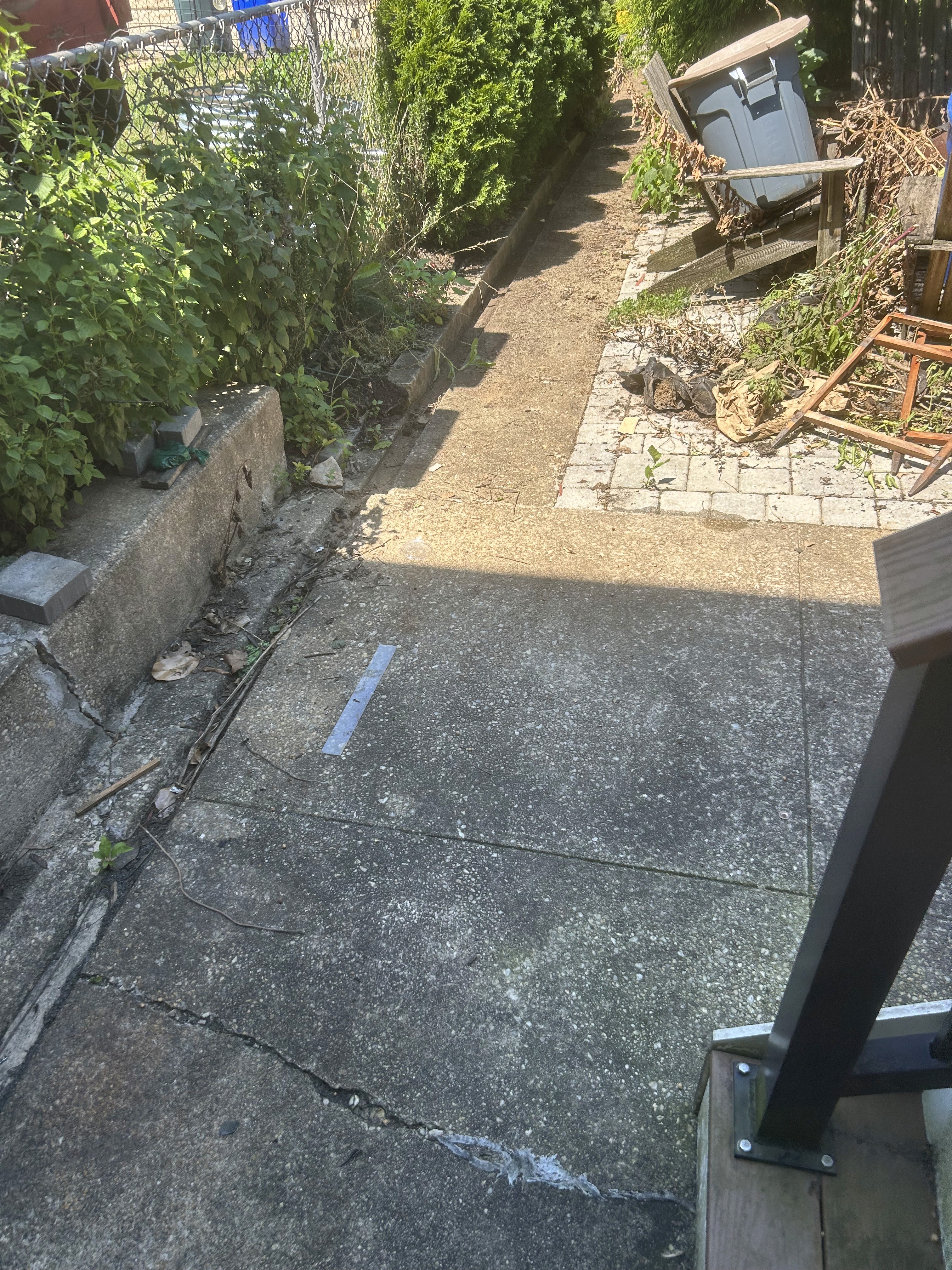 Dirty rear concrete walkway and patio area before pressure washing in Rodgers Forge.