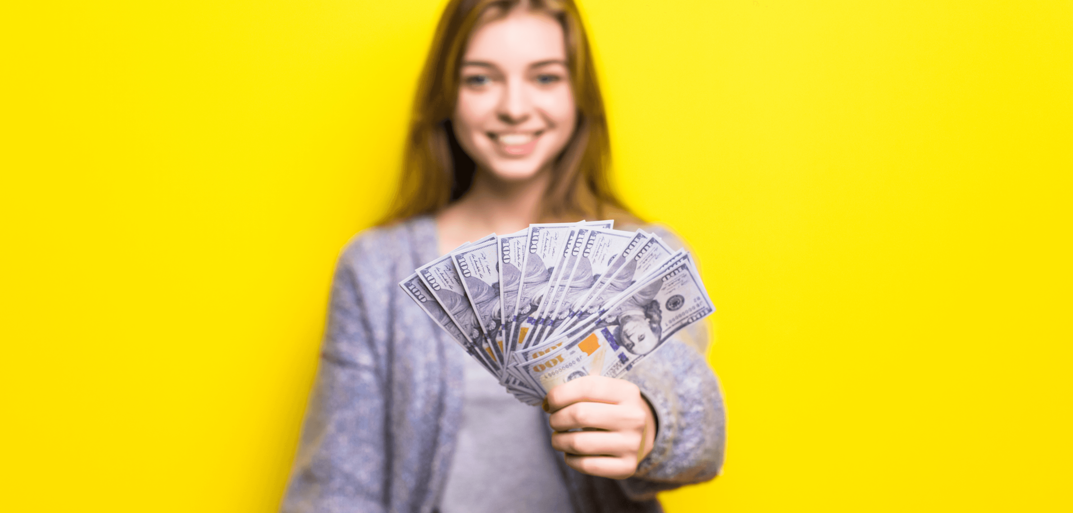 Smiling person holding a fan of US $100 bills against a bright yellow background.