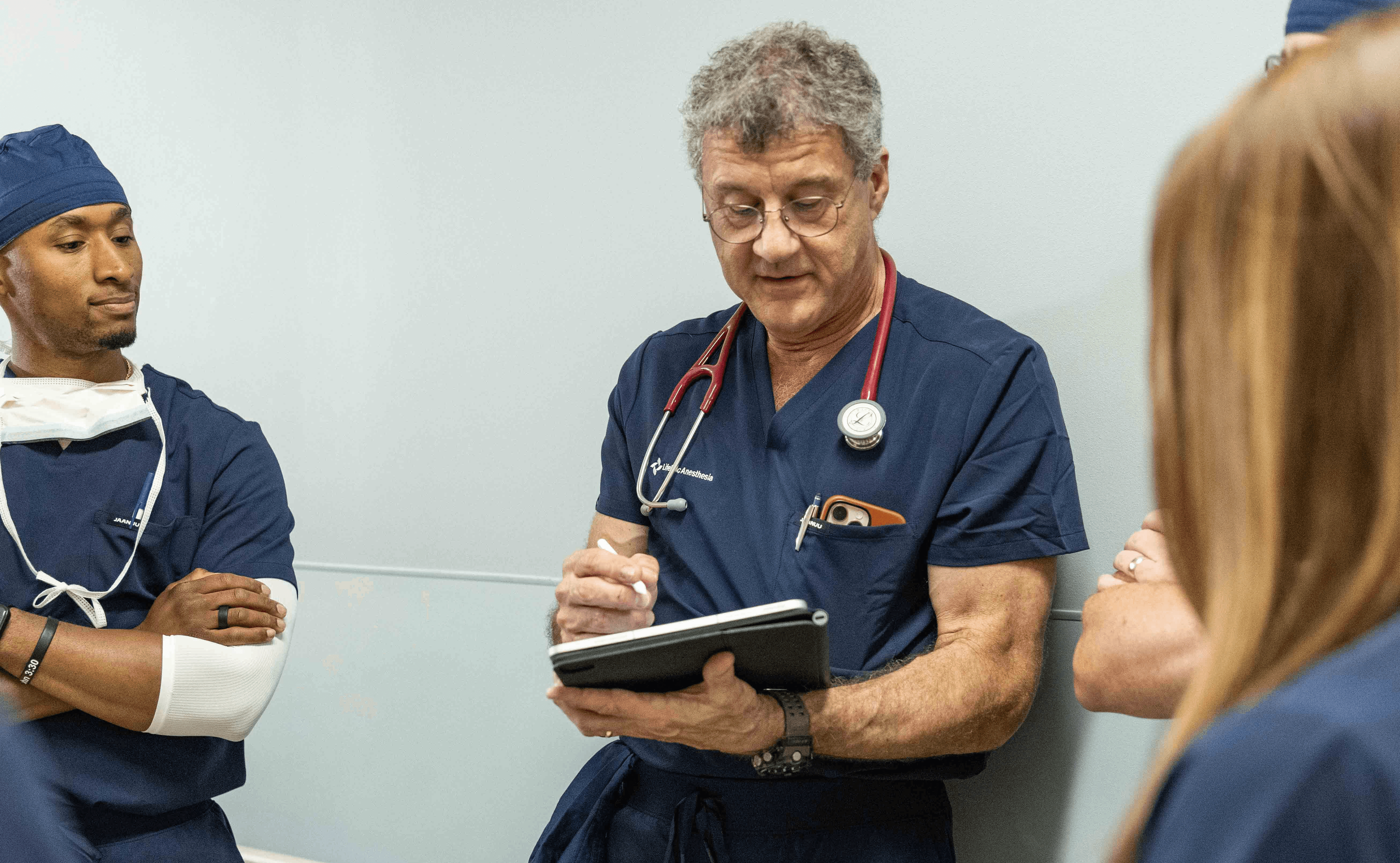 An anesthesia provider reviews case notes or a clipboard in a clinical setting, reflecting optimized workflows and operational efficiency for ASC anesthesia programs