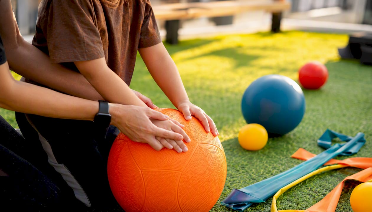 Hands guiding child in therapeutic heavy work activity