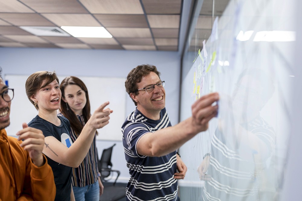 PaperKite employees arranging post-it notes on a glass screen during a collaborative session.