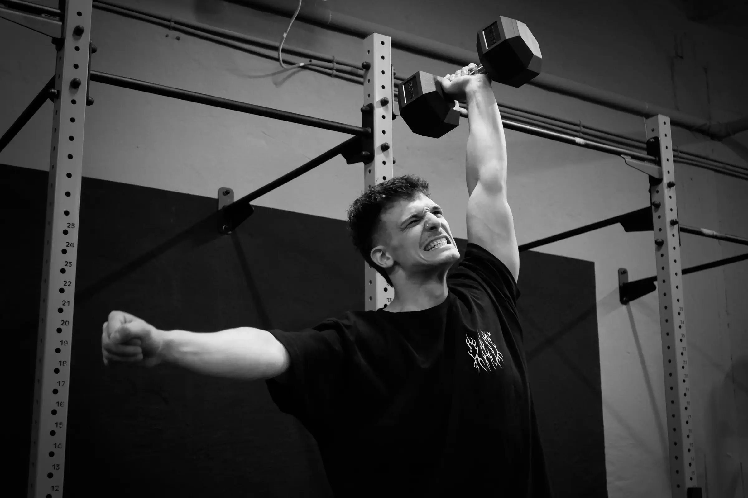 czlowiek robiacy ohs z hantlą nad głową podczas treningu w nexus gym