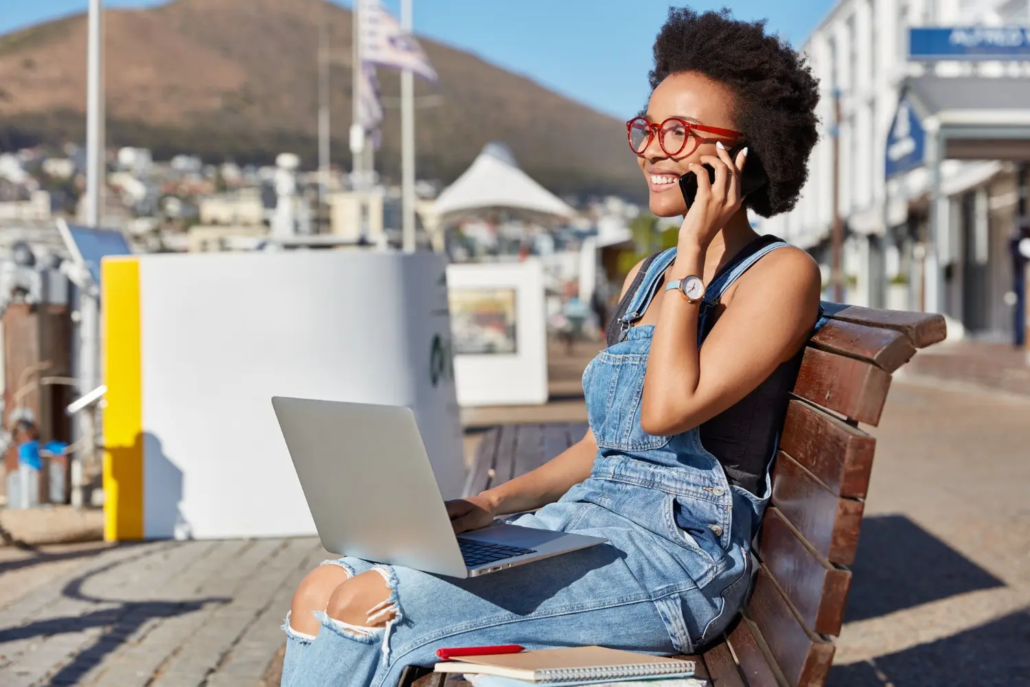 A remote worker taking a business call on her mobile while working on a laptop outdoors in Cape Town