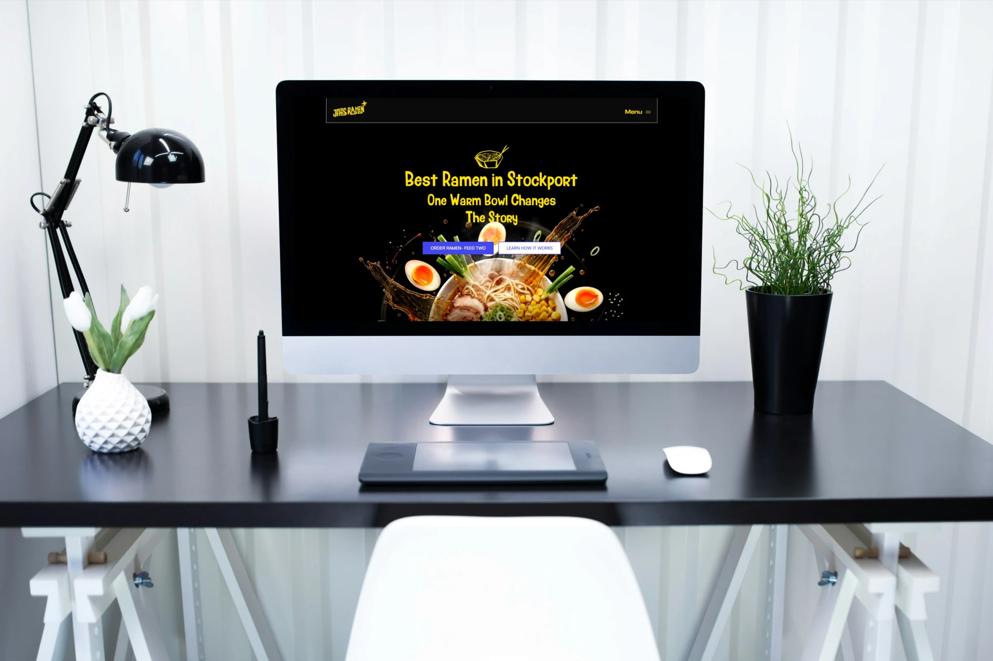 An iMac display on a modern workspace desk showcasing the minimalist homepage design for the Jefes Ramen website.