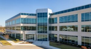 Three-story glass-fronted office building with central canopy entrance and landscaped surroundings — ideal for conversion ROI through curb appeal and adaptive reuse