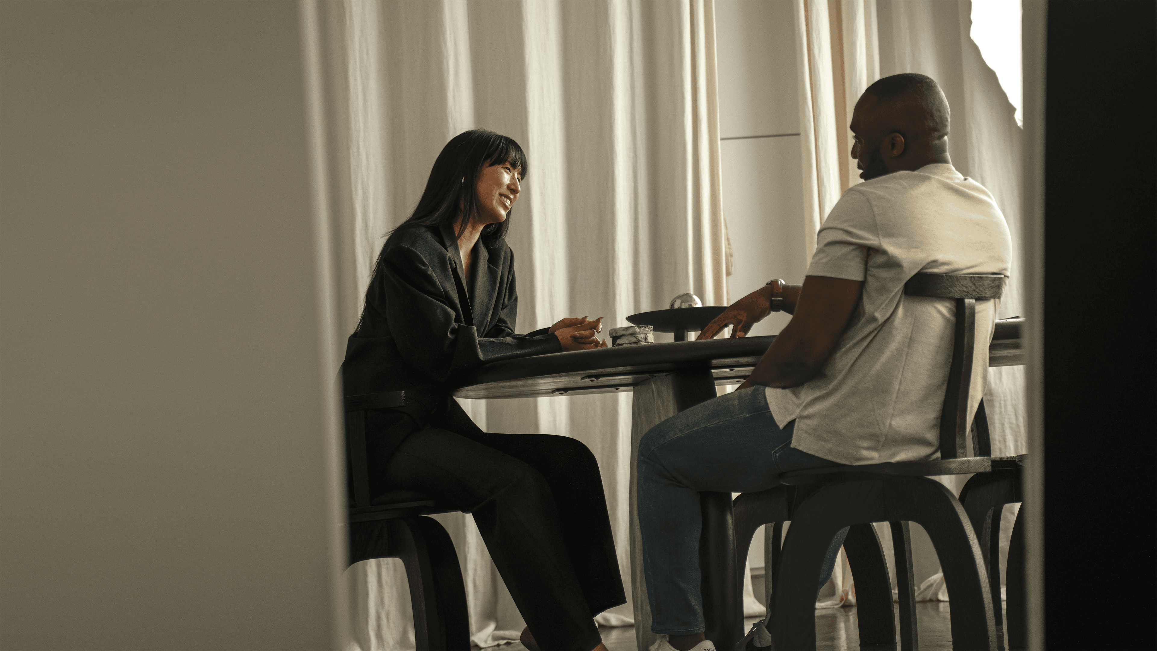 UNBLOKD CO podcast with Tade Bolarin and Ellen Yang in Japandi loft, smiling and engaged in coaching conversation.
