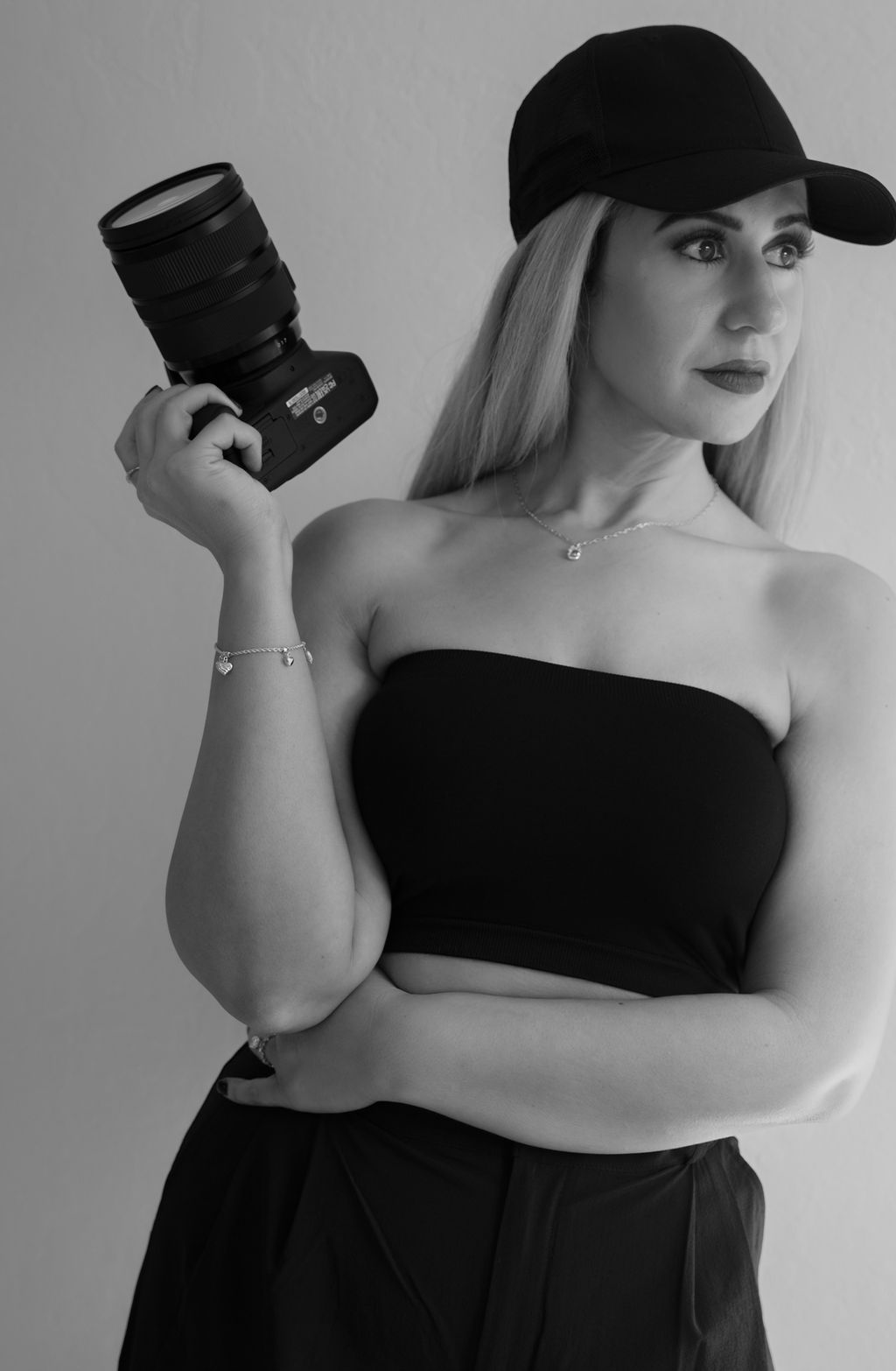 A person with shoulder-length blonde hair wearing a black newsboy cap and a black sweater.