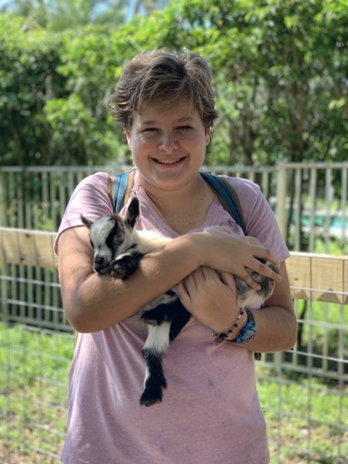 Young teen girl holding a baby donkey as teen grief support