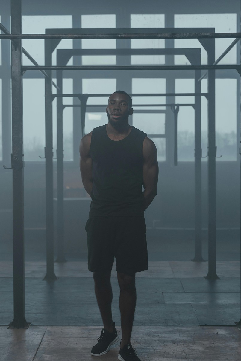Athlet im Functional-Fitness-Bereich mit Calisthenics-Rig in einer urbanen Indoor-Trainingshalle – Kraft- und Körpergewichts-Training als Ergänzung zum Bouldern.