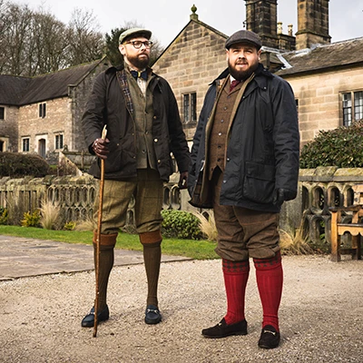 Two men, Adam Yeomans and Ben Fox of Hartingtons Heritage Tours, in Derbyshire. They wear tweed suits in brown and grey and one wears flat cap