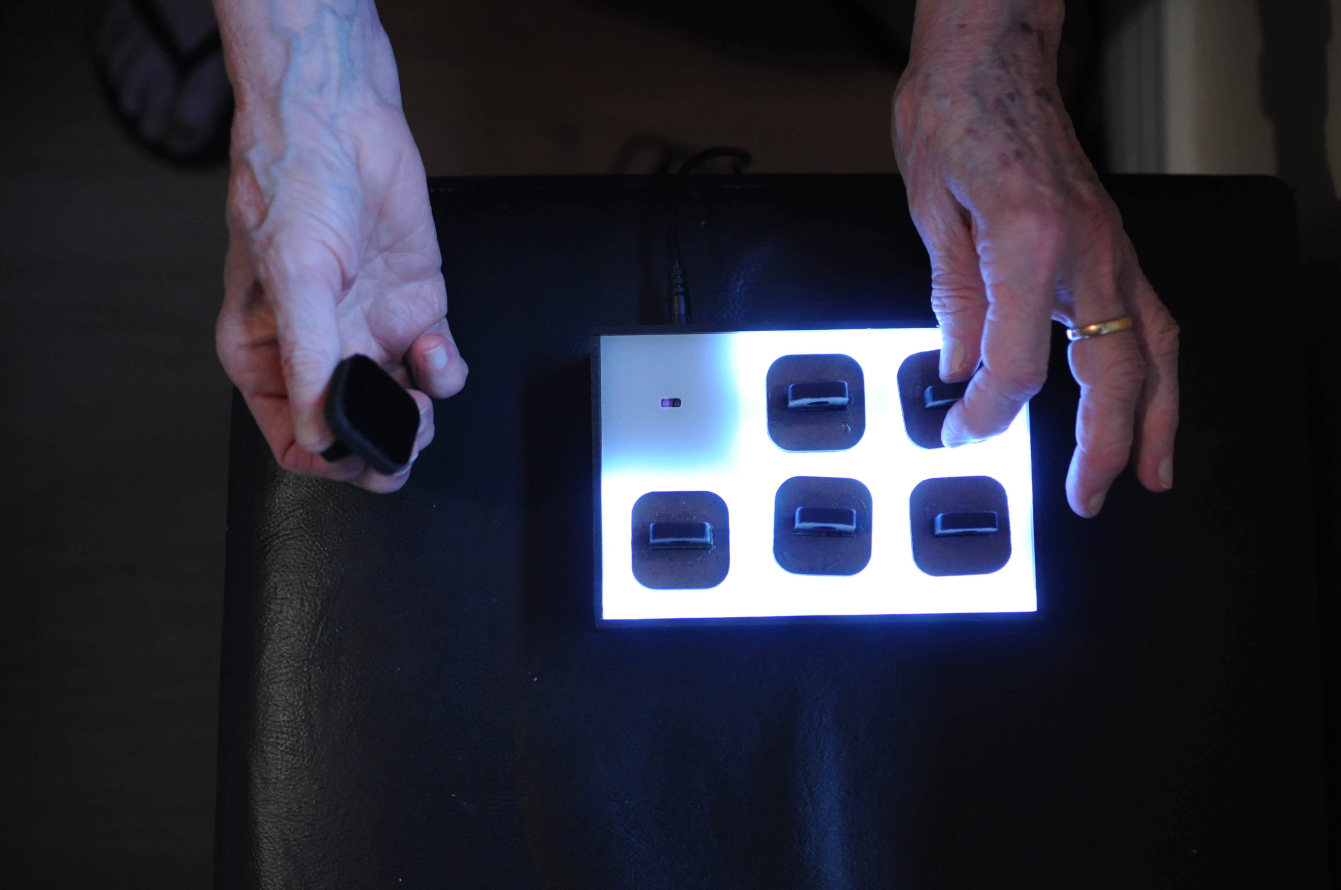 Cropped shot of a person interactiong with the prototype. Shot only shows the hands and the top view of the box.