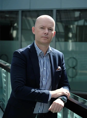 Person in a suit standing on an outdoor platform.