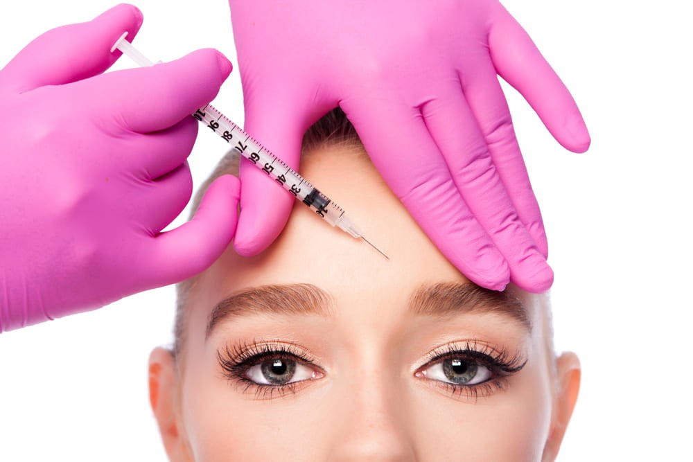 Woman getting botox injection procedure done in forehead