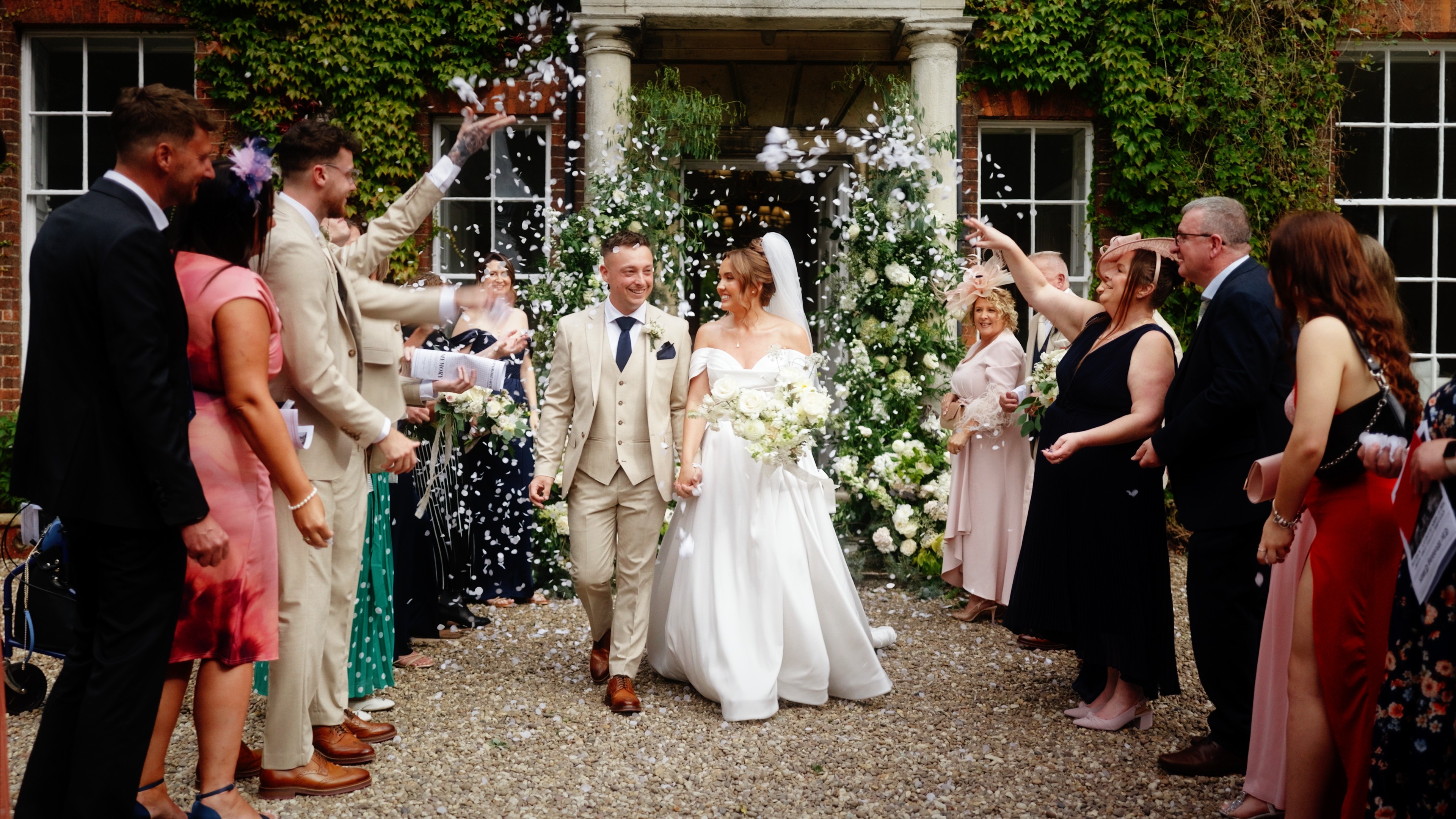 Bride and groom walking through confetti outside Wootton Hall after their wedding ceremony