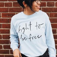 Person wearing a "fight to be free" shirt standing in front of a brick wall.