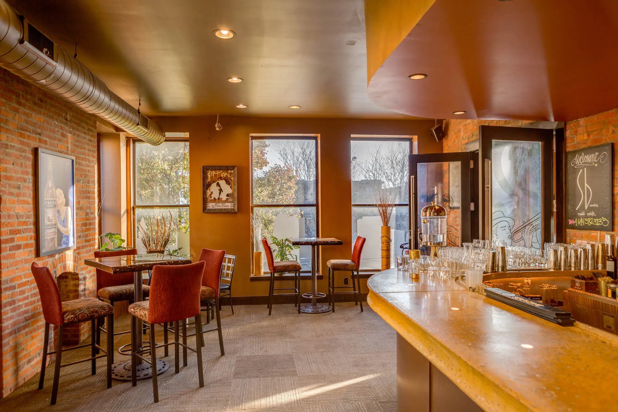Tall tables and a bar counter near the windows at Sidebar