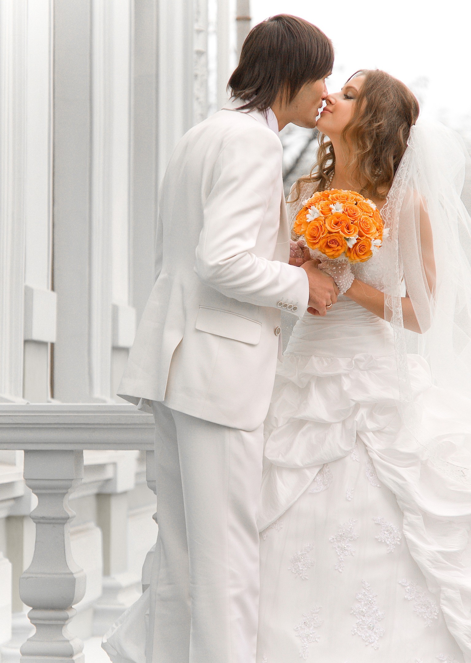Bride and groom sharing a romantic kiss in elegant white wedding attire outdoors in Atlanta