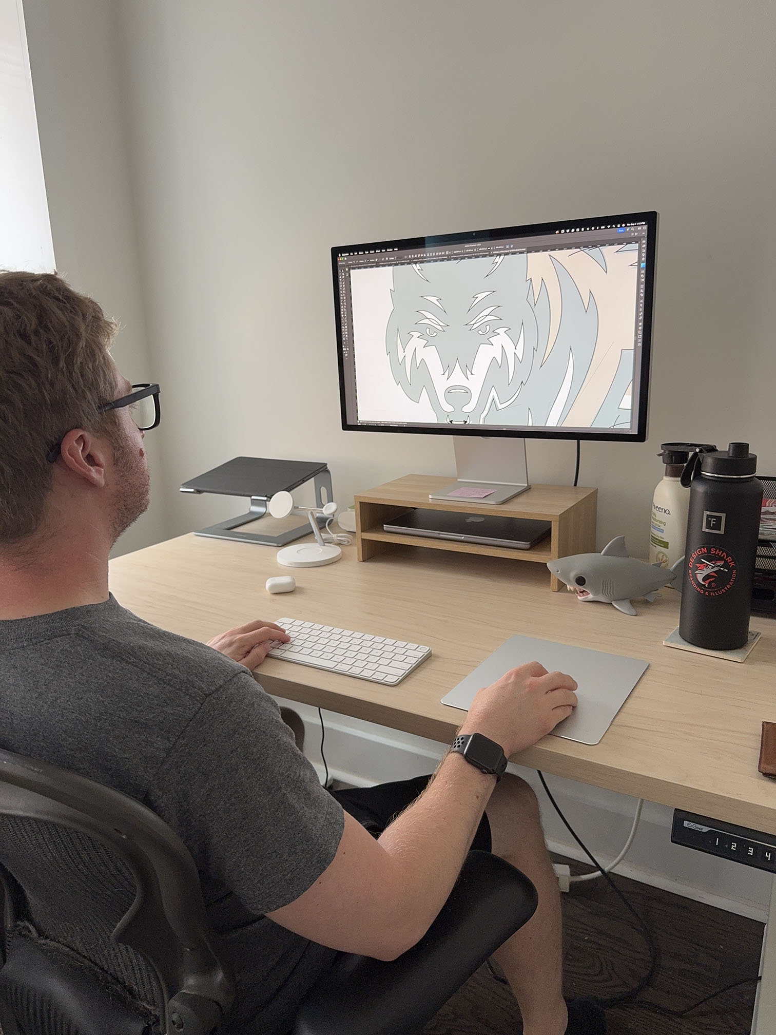 A greyscale photo of Dan Blessing, at his desk working on a branding project.