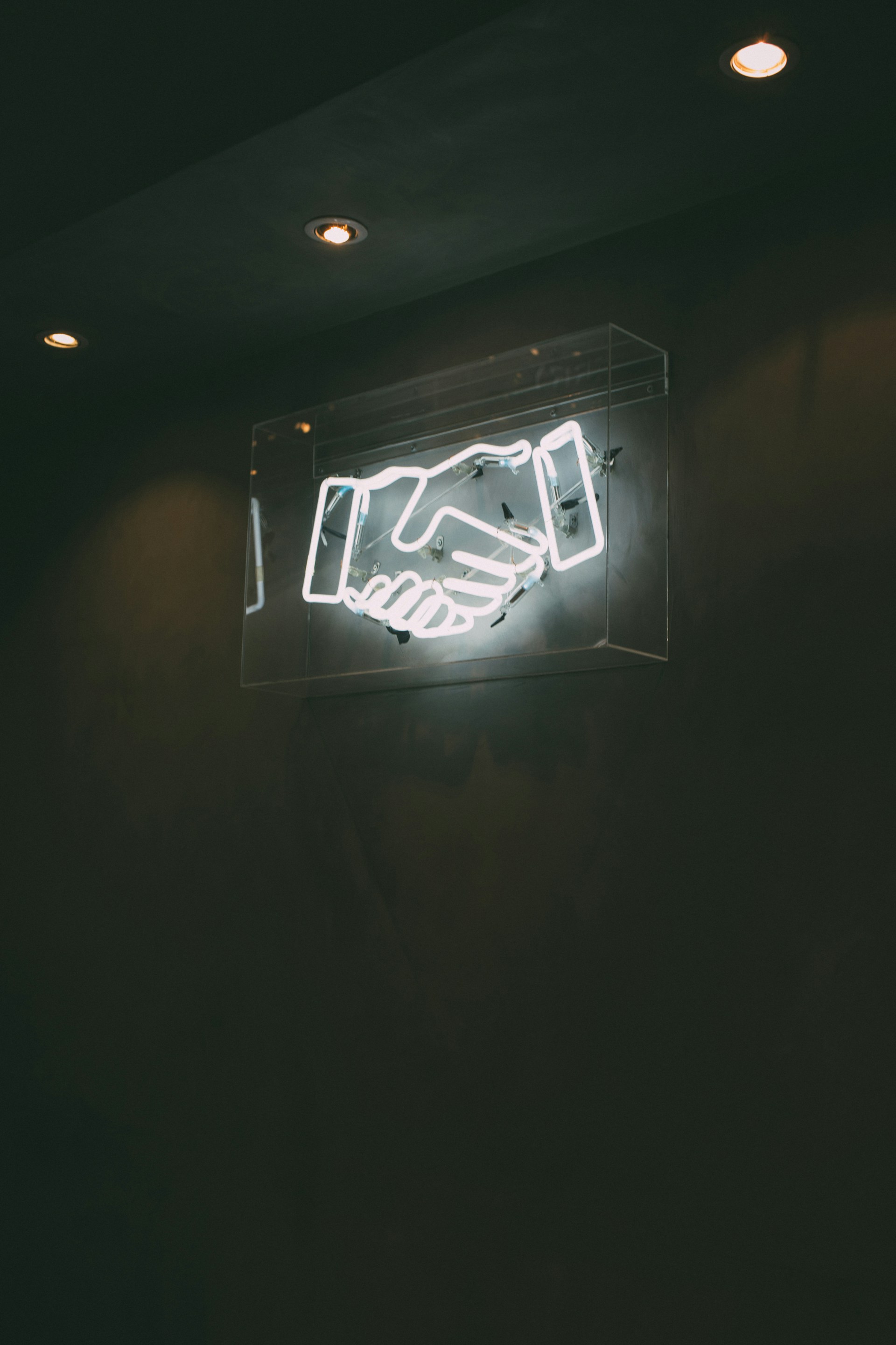 A white neon billboard of a handshake.