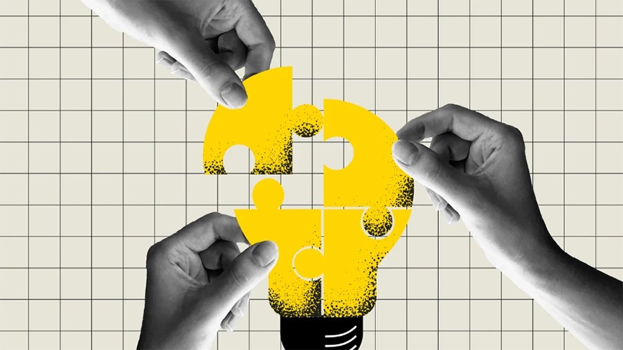 Hands assembling yellow puzzle pieces forming a lightbulb, symbolizing teamwork and incremental innovation.