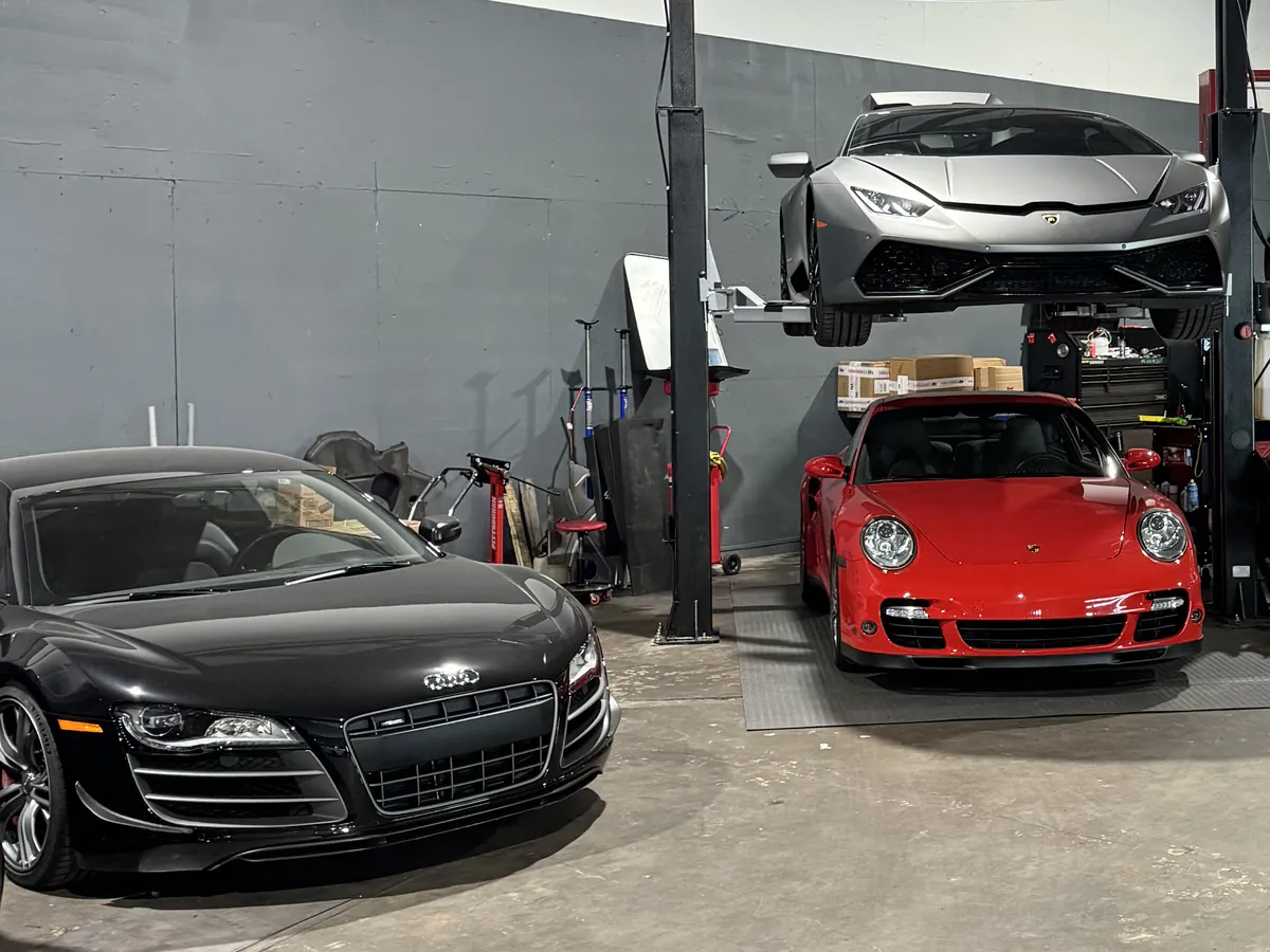 Black Audi on the workshop floor beside two cars on a lift
