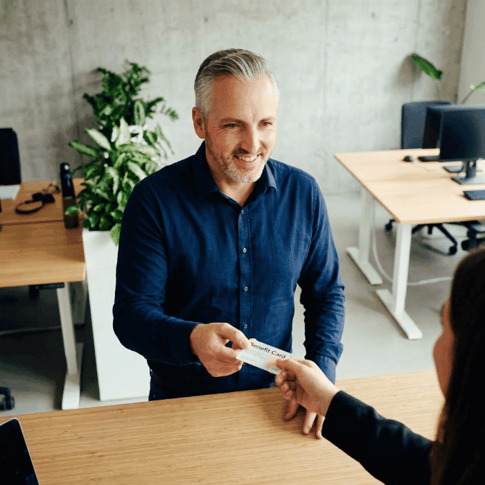 Hannes Weindorf übergibt einem Mitarbeiter die bKV-Benefit-Karte im Büro