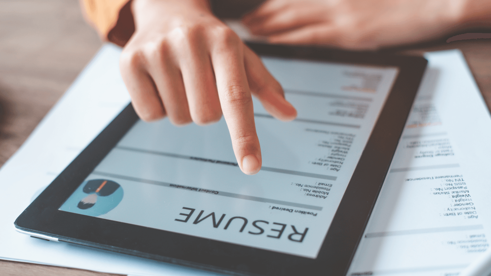 Close-up of a hand interacting with a digital resume displayed on a tablet.