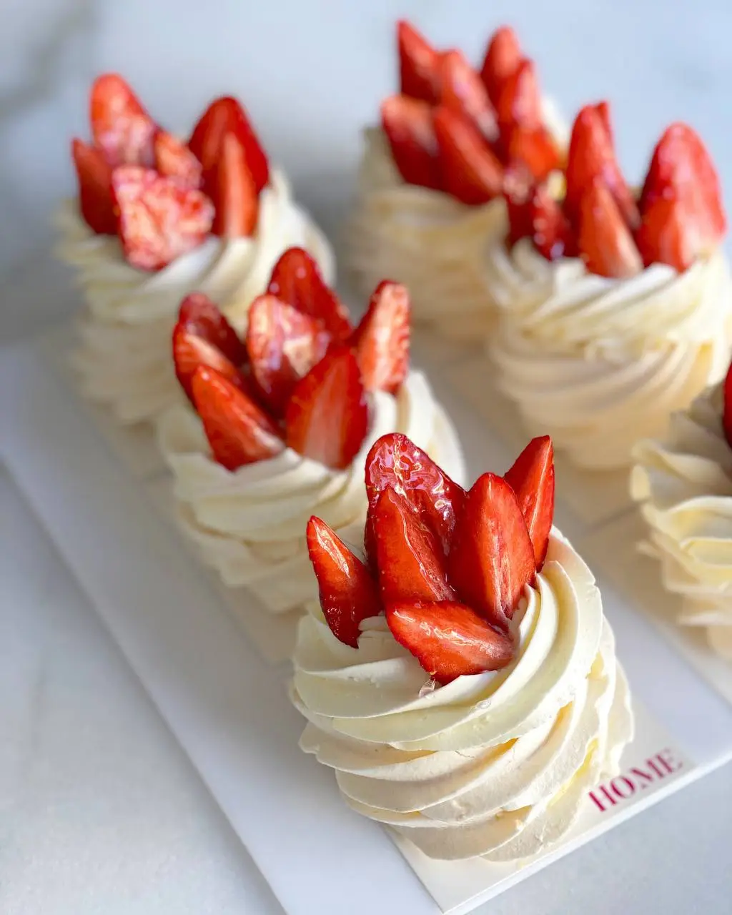 Vanilla cake decorated with fresh strawberries and cream dollops